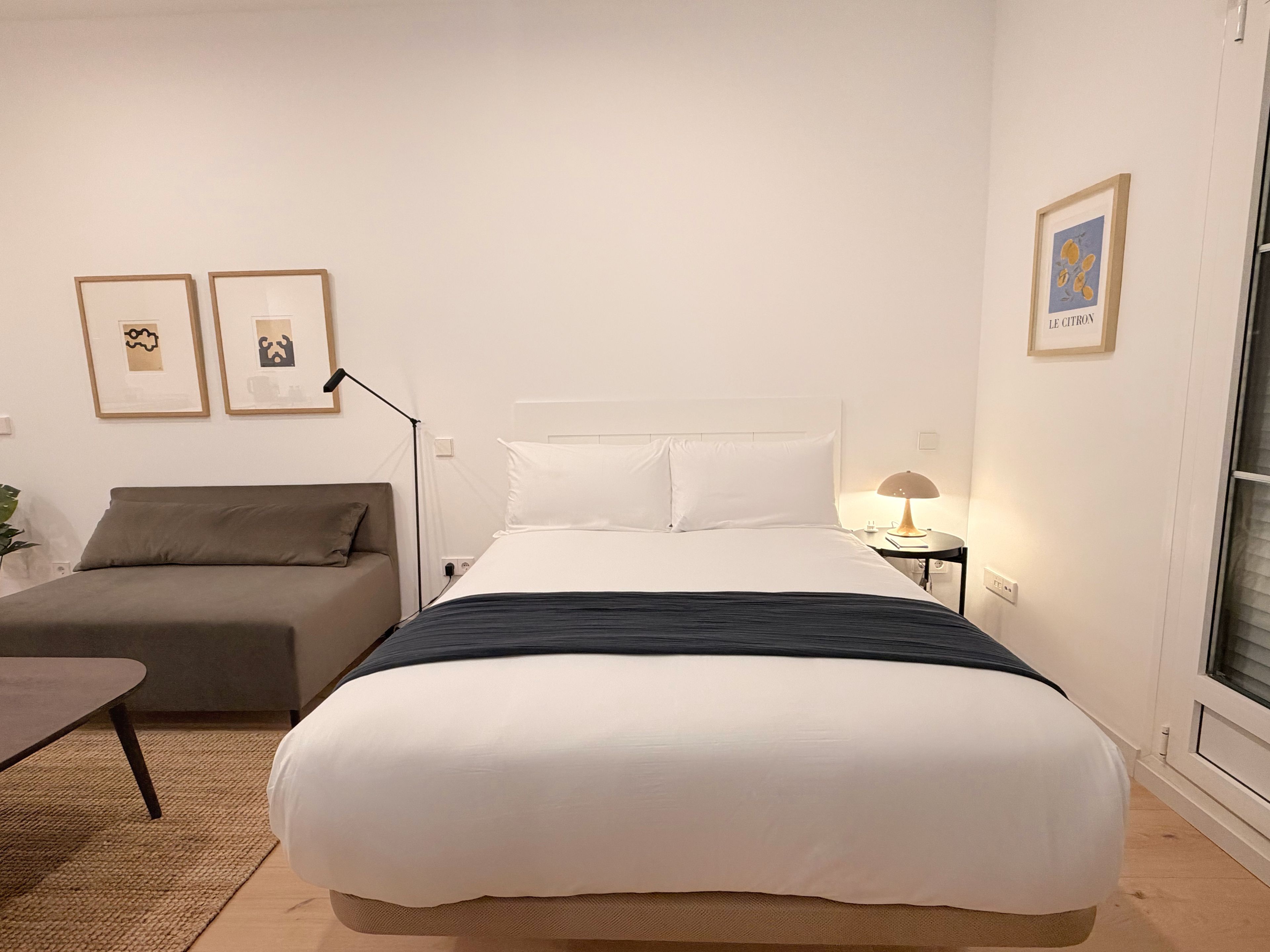 Une chambre d’hôtel avec un lit, un canapé, une lampe et deux tableaux encadrés au mur.