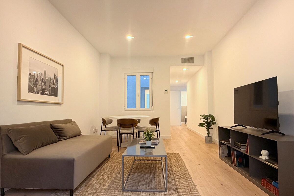 A modern living room with a sofa, coffee table, and TV stand.
