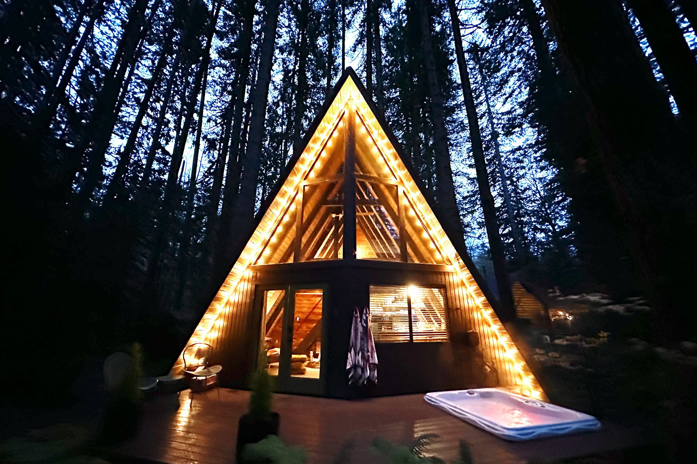 Eine dreieckige Holzhütte mit geneigtem Dach, umgeben von einem Wald.
