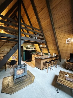Ein gemütlicher Dachbodenraum mit Küchenzeile, Kamin und Sitzgelegenheit.