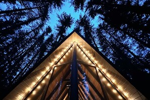 Eine dreieckige Konstruktion mit einer zentralen Säule und Holzleisten, umgeben von Bäumen.
