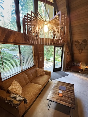 A cozy room with a wooden sofa, a coffee table, and a unique light fixture.
