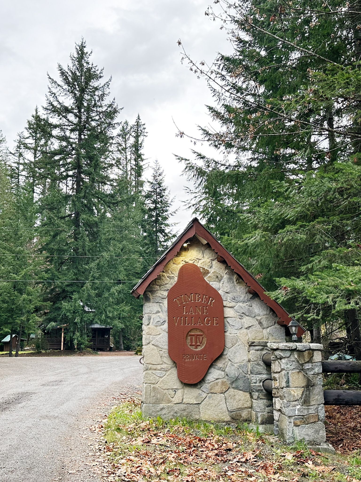 Un letrero de piedra con la leyenda 'Timber Lane Village' y 'PROPIEDAD PRIVADA', rodeado de árboles.