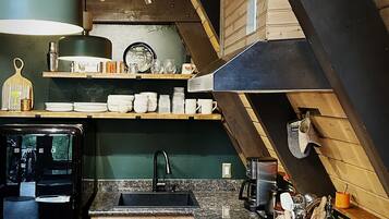 A kitchen with a wooden ceiling, a built-in stove, and a sink.