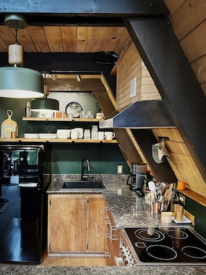 A kitchen with a wooden ceiling, a built-in stove, and a sink.