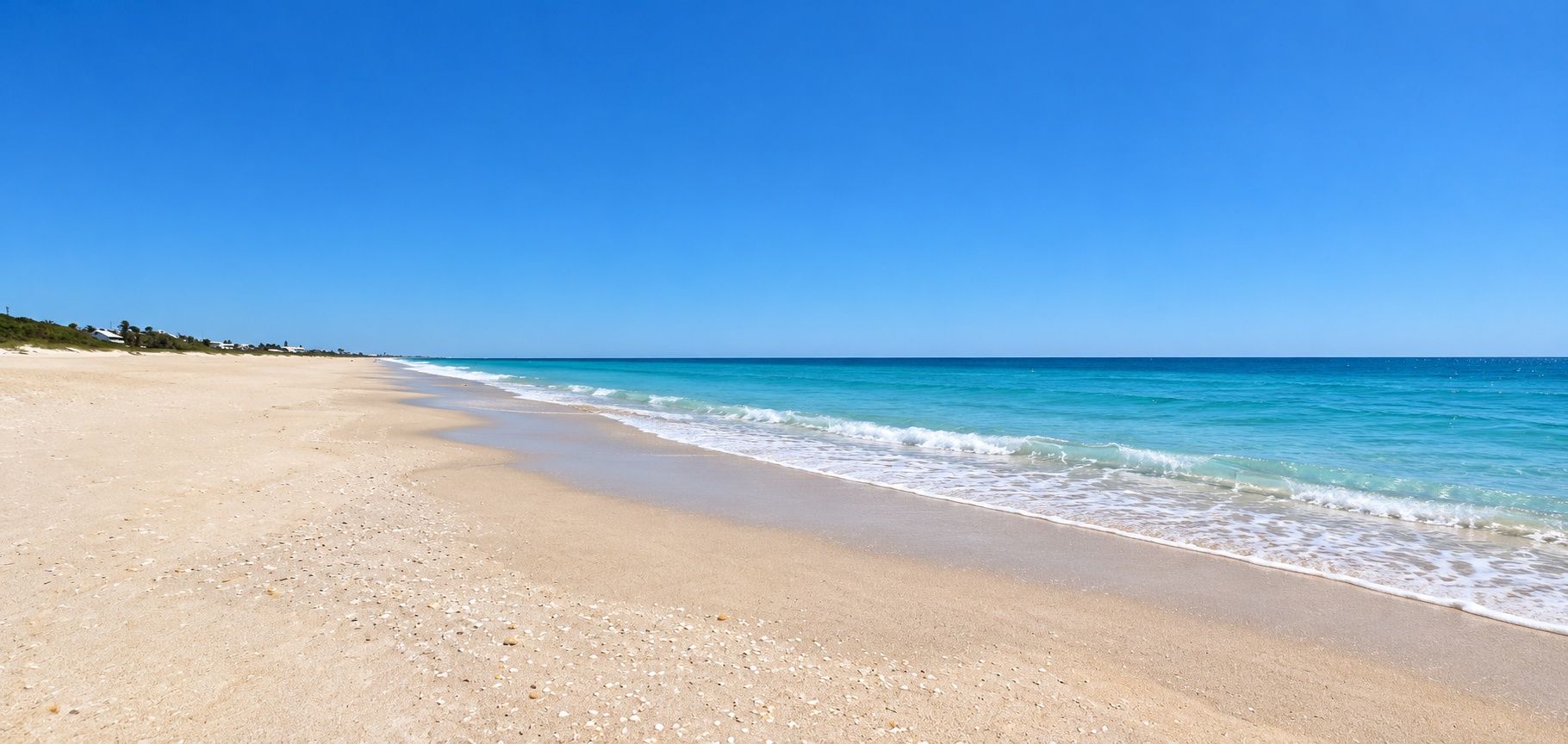 Een strand met heldere lucht en een rustige zee.