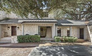 A stone house with a covered porch, a front door, and a small garden area. - Waterfront Lake LBJ Retreat, Dock Deck & Stunning Sunsets (Kingsland)
