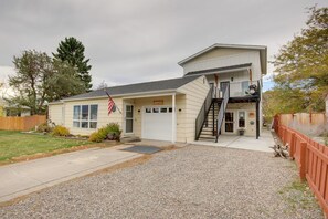 A single-story house with a front porch, a garage, and a small outdoor area with a wooden fence. - Livingston Loft | Mountain Views Near Downtown (Livingston)