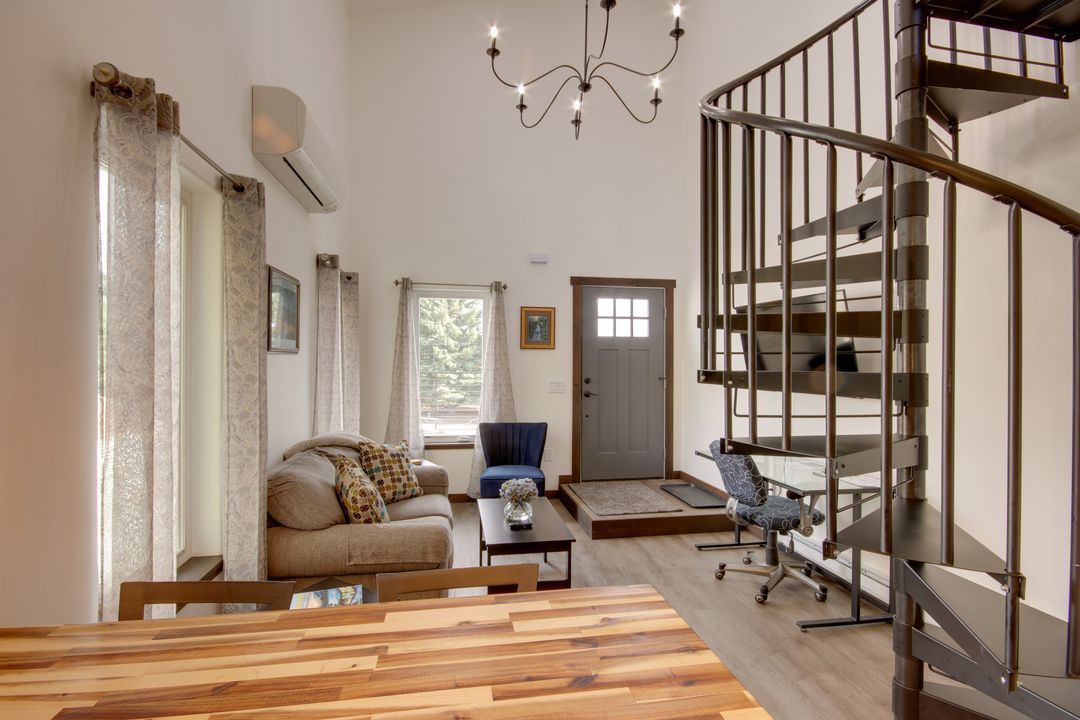 Un salon avec un escalier, un canapé, une table basse et un fauteuil.