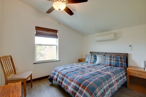 A bedroom with a bed, a chair, a nightstand, a ceiling fan, and a window with blinds. - Livingston Loft | Mountain Views Near Downtown (Livingston)