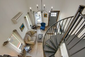 A living room with a sofa, a blue armchair, a coffee table, and a staircase. - Livingston Loft | Mountain Views Near Downtown (Livingston)