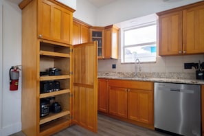 A kitchen with wooden cabinets, a stainless steel dishwasher, and a window providing natural light. - The Dolphin Retreat, Huge Pool & Boat Parking (Marathon)