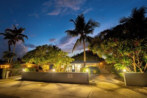 A well-lit outdoor area with palm trees, a building with a sign, and a paved walkway. - The Dolphin Retreat, Huge Pool & Boat Parking (Marathon)