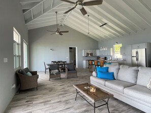 A spacious living room with a high ceiling, a dining area, and a kitchen with modern appliances. - Modern 2BR St Croix Home with an Amazing Ocean View (Christiansted)