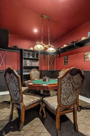A room with a green pool table, four ornate chairs, a bookshelf, and a hanging light fixture. - Outlaw Rest | Hot Tub, Pickleball, Views, Game Room, Poker, Grand Canyon (Williams)
