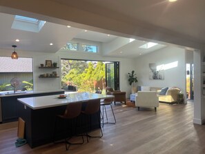 A spacious kitchen with a central island, large windows, and a view of the outdoors. - Bright + spacious home w/ sauna. Steps to ocean, bluff-top trail, and downtown (Half Moon Bay)
