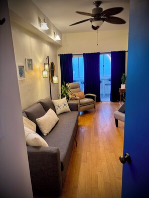 A living room with a sofa, armchairs, a ceiling fan, and a view to the outside. - Boutique Surf Hideaway Steps from the Pacific (Manhattan Beach)