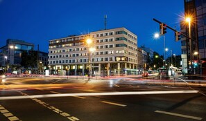 Ein mehrstöckiges Gebäude mit flacher Fassade, zahlreichen Fenstern und einem zentralen Eingang.
