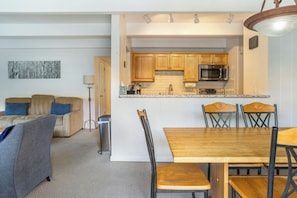 Ett kompakt bostadsutrymme med ett litet kök, en matplats och en sittgrupp.
