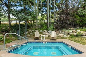 A swimming pool with a metal ladder, two Adirondack chairs, and a stone wall with rocks and plants. - Vantage Point 309 - Heart of Lionshead, Walk to slopes (Vail)