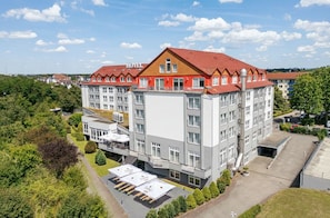 Ein Hotel mit mehreren Etagen, einem roten Dach und einem zentralen Innenhof mit Außenbestuhlung.