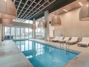 An indoor swimming pool with lounge chairs and hanging lamps. - Charming 2-bedroom apartment with AC in lovely Montréal (Montréal)