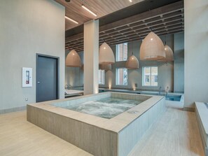 A modern spa room with a central hot tub, pendant lighting, and large windows. - Charming 2-bedroom apartment with AC in lovely Montréal (Montréal)