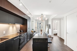 A modern kitchen with dark cabinetry, a wooden countertop, and a central island. - Charming 2-bedroom apartment with AC in lovely Montréal (Montréal)