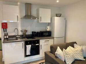 Una cocina compacta con campana extractora de acero inoxidable, horno empotrado, microondas y refrigerador blanco.