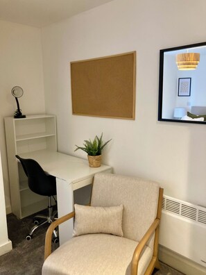 A room with a white desk, a black office chair, a beige armchair, a potted plant, a corkboard, and a framed picture on the wall. - Fargate Central 204 | 3-Bed | Sheffield Centre (Sheffield)
