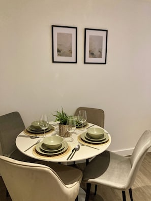 A dining table set with green plates, glasses, and cutlery, surrounded by chairs. - Fargate Central 204 | 3-Bed | Sheffield Centre (Sheffield)