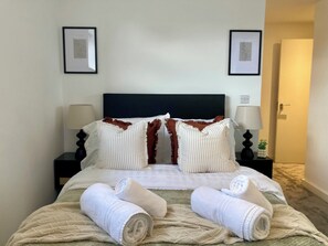 A hotel room with a bed, two bedside lamps, a framed picture on the wall, and a door. - Fargate Central 204 | 3-Bed | Sheffield Centre (Sheffield)