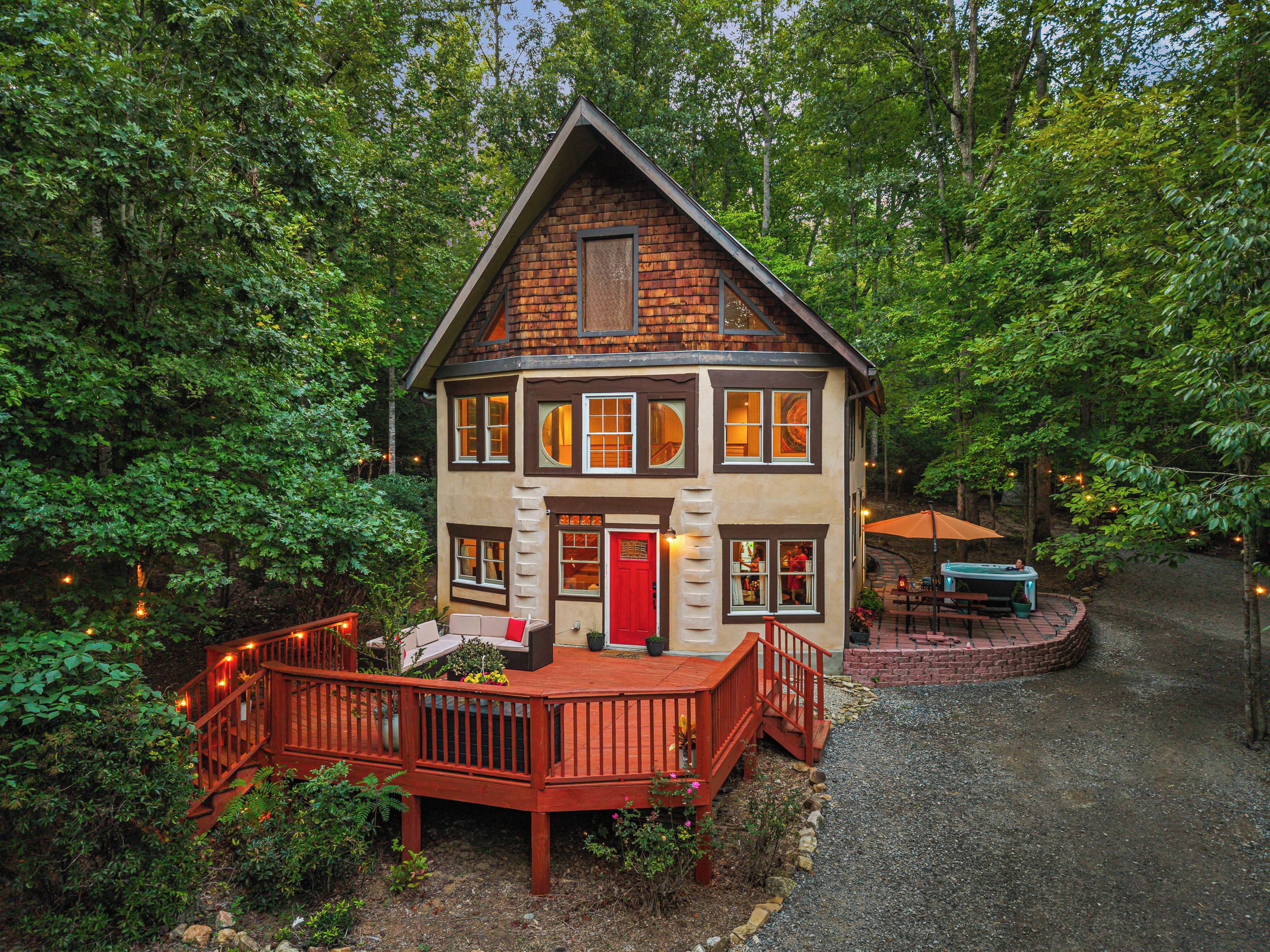 A two-story house with a deck, surrounded by trees.
