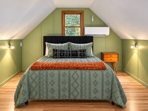 A bedroom with a sloped ceiling, a bed with patterned bedding, a nightstand, and wall-mounted lighting. - Private 30-Acre Retreat w/ Hot Tub, Game House/Pool Table, Trails & Pet Friendly (Old Fort)