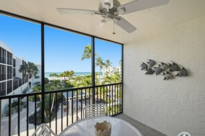 Ein Balkon mit Blick auf den Strand, ein Deckenventilator und eine Wanddekoration.