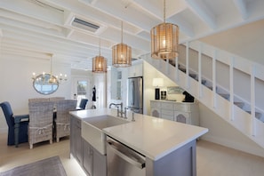 A modern kitchen with a central island, stainless steel appliances, and a staircase leading to an upper level. - Gulf-Front Bliss | Soothing Waves, Breathtaking Sunsets & the Peaceful Charm of Boca Grande (Boca Grande)