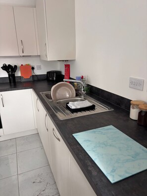 A kitchen with a sink, countertop, and cabinets. - Spacious 3-bedroom Apartment Near Norfolk Beach (Sheringham)
