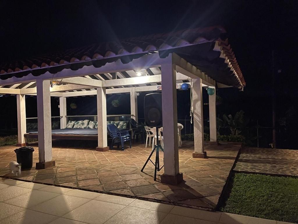 A covered outdoor area with a bed, chairs, and a grill.