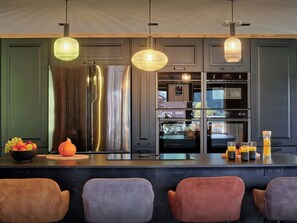 A modern kitchen with stainless steel appliances, a fruit bowl, and a bar area with seating. - Ferme V - High-end chalet with spa facilities and gym - OVO Network (Saint-Jean-d'Aulps)