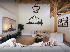 A modern living room with a large sofa, a coffee table, a fireplace, and a wall with a Paramount movie poster and a mountain silhouette decal. - Ferme V - High-end chalet with spa facilities and gym - OVO Network (Saint-Jean-d'Aulps)