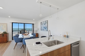 A modern kitchen with a marble countertop, stainless steel sink, and a view of the ocean. - Sea Oats | Feel the Gulf Breezes, Escape the Everyday & Rediscover the Joy of Island Living (Boca Grande)
