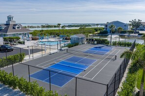 A tennis court area with a pool, a gazebo, and a view of the water. - BG North 81 | Top-Floor Gulf Escape—Golden Sunsets, Endless Skies, Soothing Surf & Pickleball (Boca Grande)