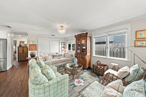 A spacious living room with a large sofa, a dining area, and a kitchen in the background. - 271 Lee Cottage | Quaint Boca Grande Village Charm—Stroll to Shops, Dining & Island Life (Boca Grande)