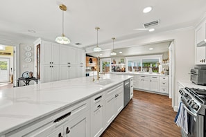 A spacious kitchen with white cabinetry, a large island, and a wood floor. - 271 Lee Cottage | Quaint Boca Grande Village Charm—Stroll to Shops, Dining & Island Life (Boca Grande)