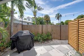 A backyard with a barbecue grill, a wooden fence, and a house in the background. - 271 Lee Cottage | Quaint Boca Grande Village Charm—Stroll to Shops, Dining & Island Life (Boca Grande)