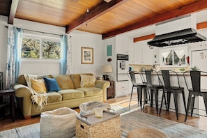 A cozy living room with a sofa, a coffee table, and a dining area with chairs and a table. - The Little Pine | Cozy 2BR | Crestline (Crestline)
