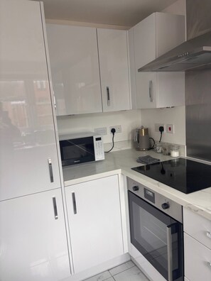 A modern kitchen with white cabinetry, a built-in oven, and a stovetop. - Hidden Gem With Enclosed Garden and Parking (Sheringham)