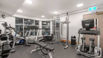 A gym with various exercise equipment, including treadmills, weight machines, and a bench.