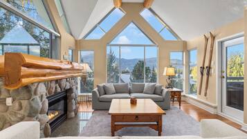 A spacious living room with a stone fireplace, a large window offering a mountain view, and a cozy seating area.
