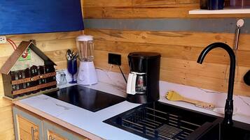 A kitchen with wooden cabinets, a double sink, a coffee maker, and a blender.